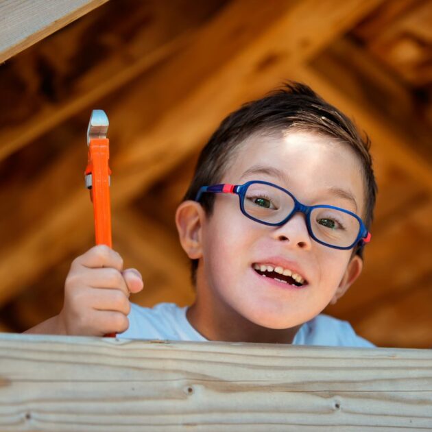 Little boy holding a toy wrench and screwdriver.