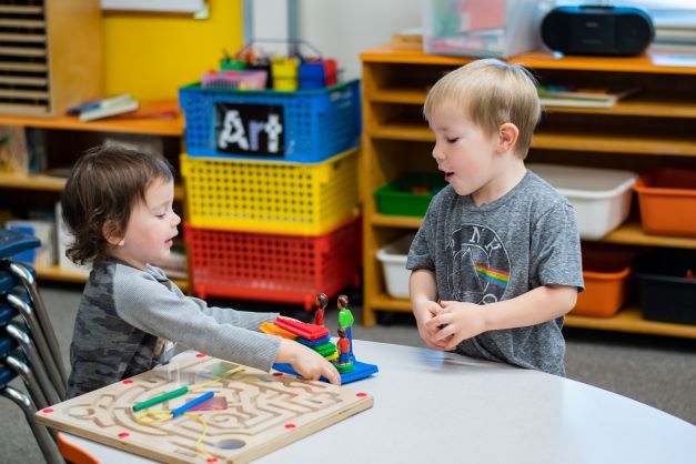 Two young children playing at a table in a classroom.
