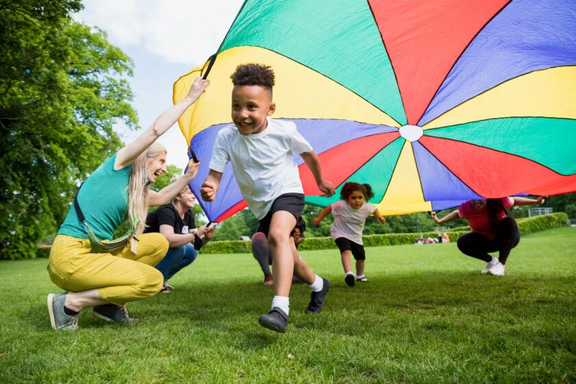 A group of children playing with a colorful parachute in a park.